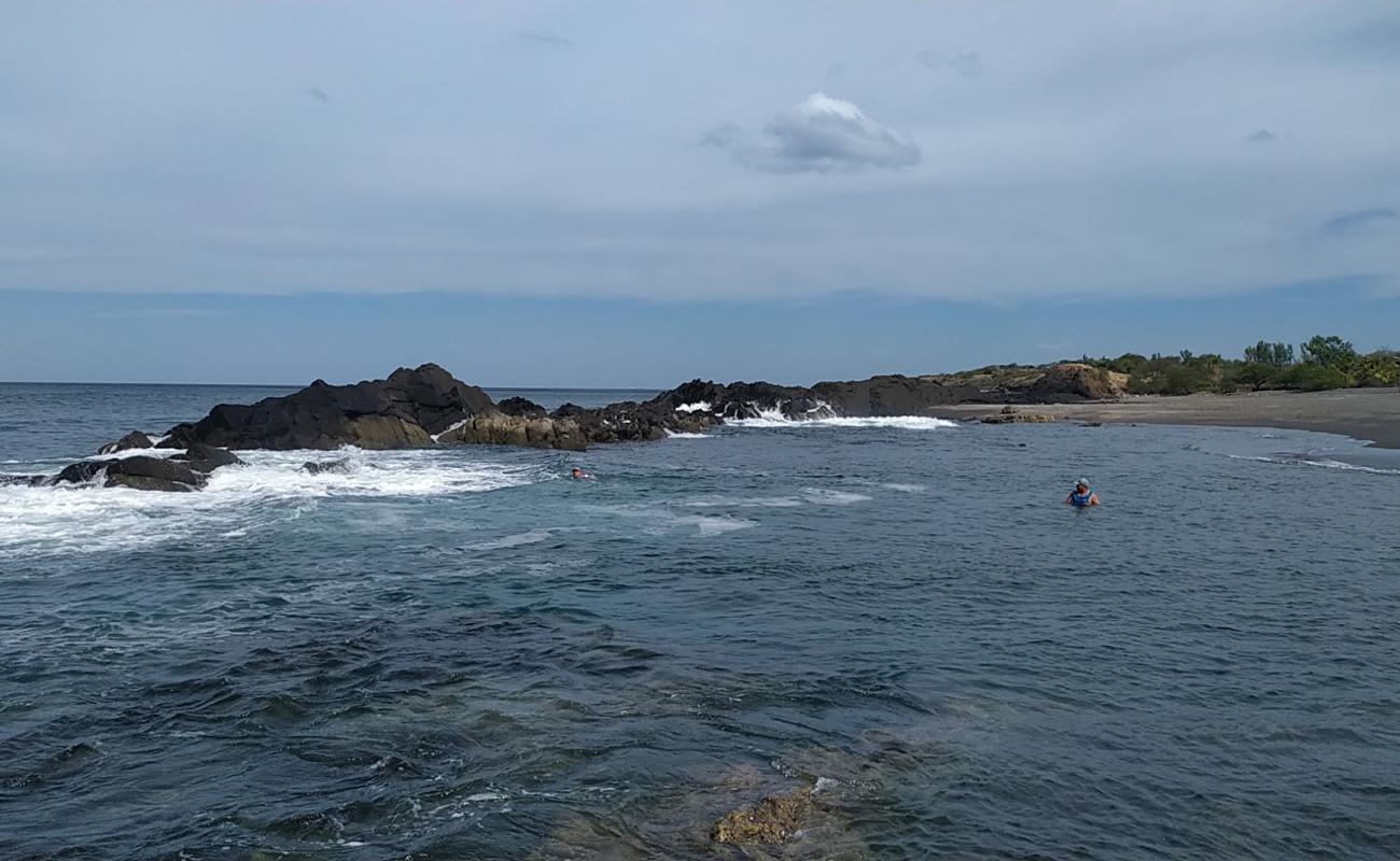 Photo de La Mona beach avec sable gris & rochers de surface