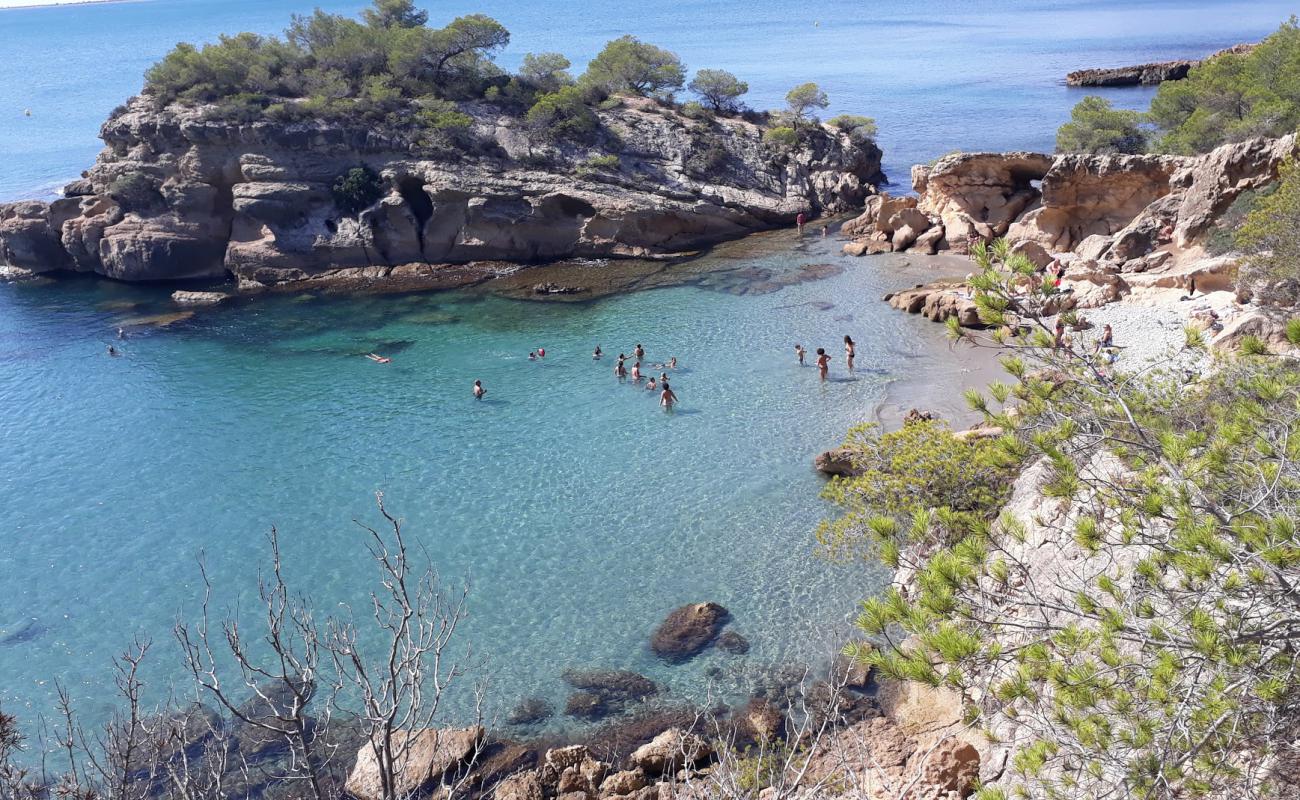 Photo de Cala de l'Aliga avec sable brun avec roches de surface