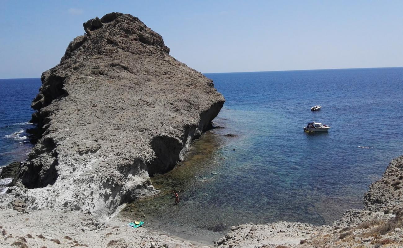 Photo de Cala de las Hermanicas avec sable gris avec roches de surface