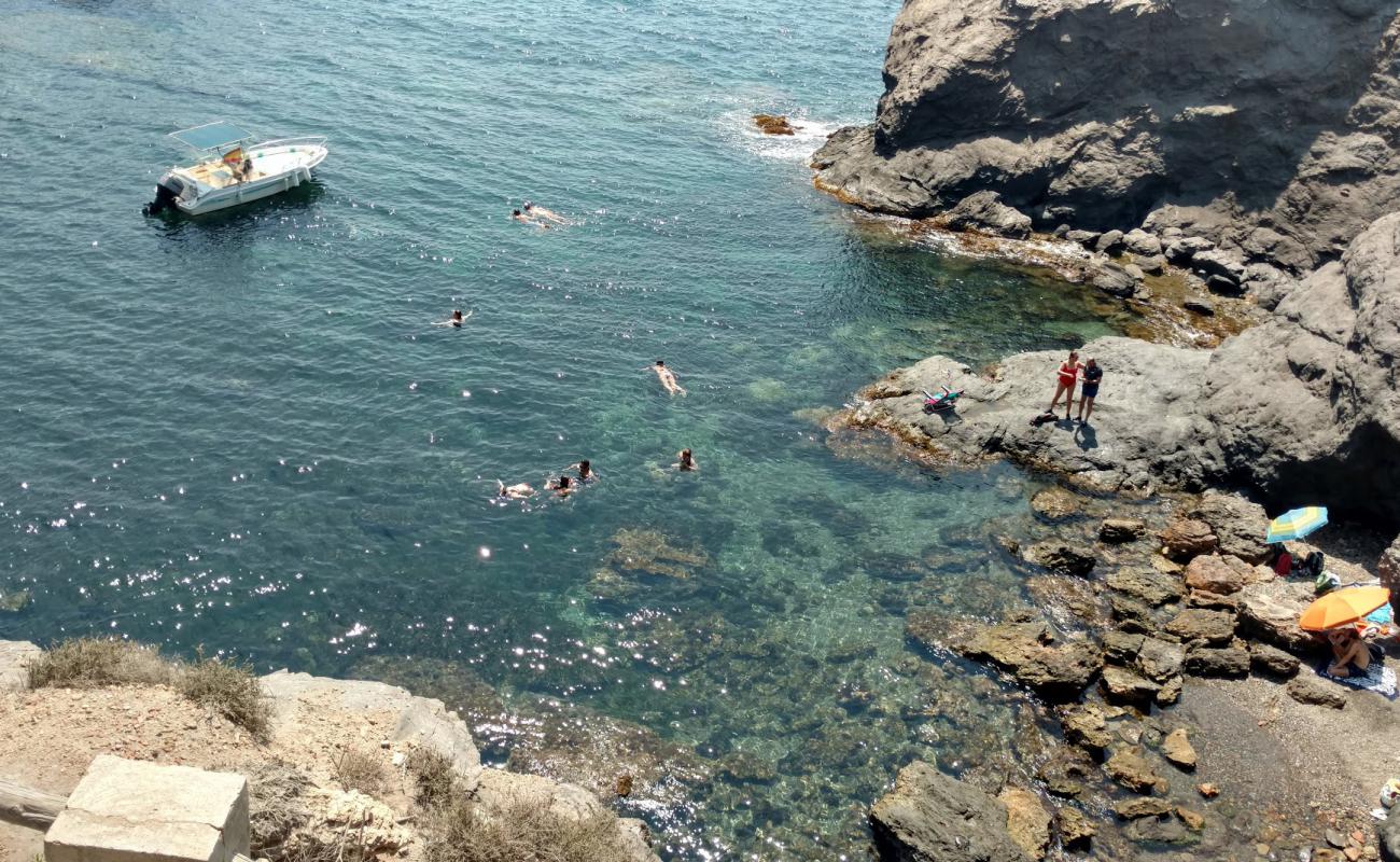 Photo de Cala de las Melvas avec sable noir avec caillou de surface