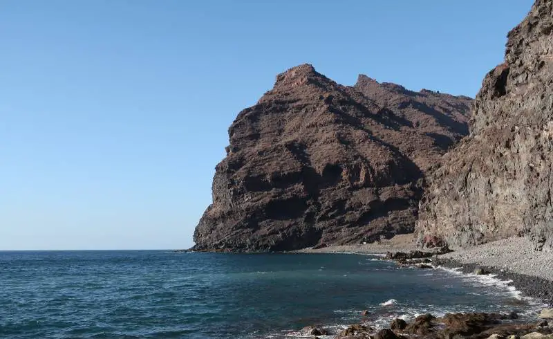 Photo de Playa de Tasartico avec sable gris & rochers de surface